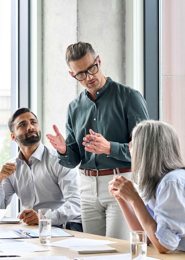 a group of people are sitting around a table having a meeting