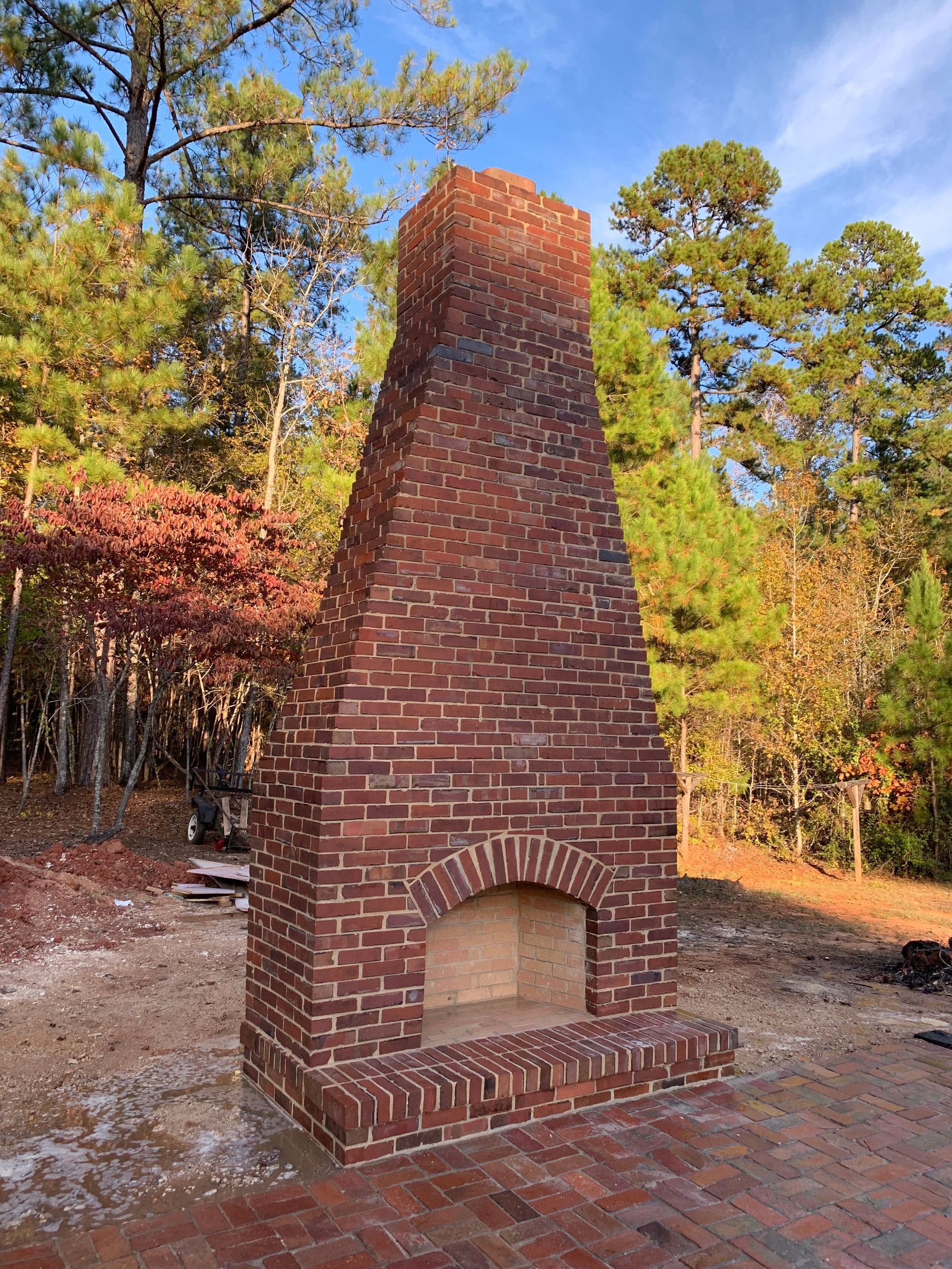 A large brick fireplace is sitting in the middle of a forest.