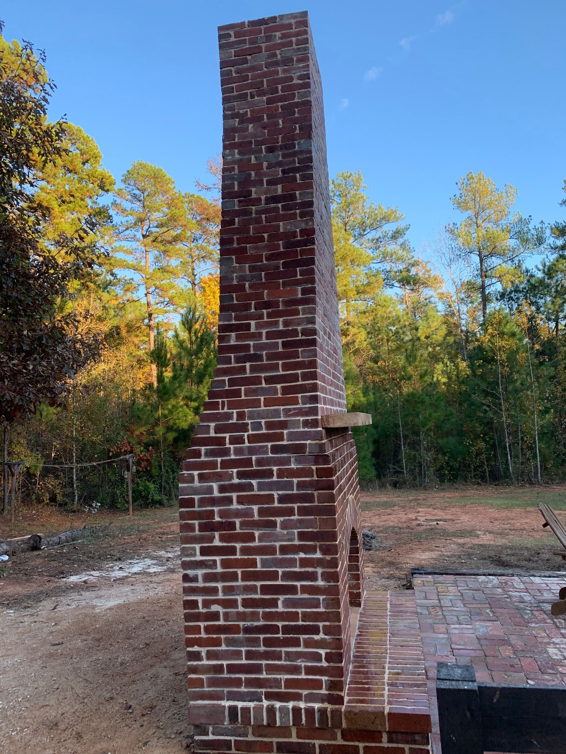 A large brick chimney is in the middle of a forest.