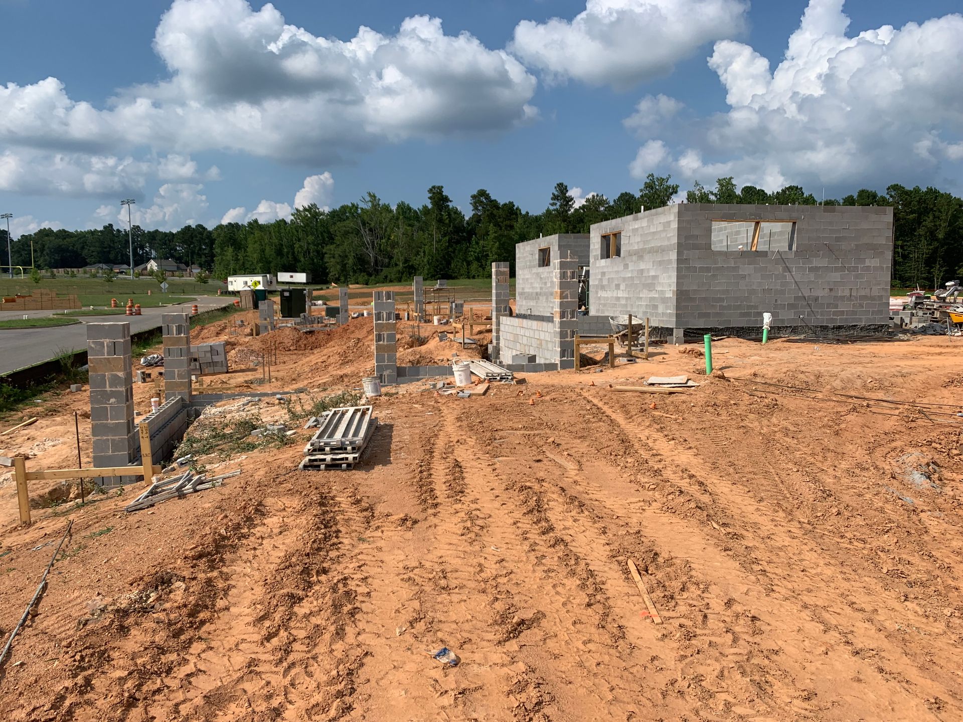 A brick building is being built in a dirt field.