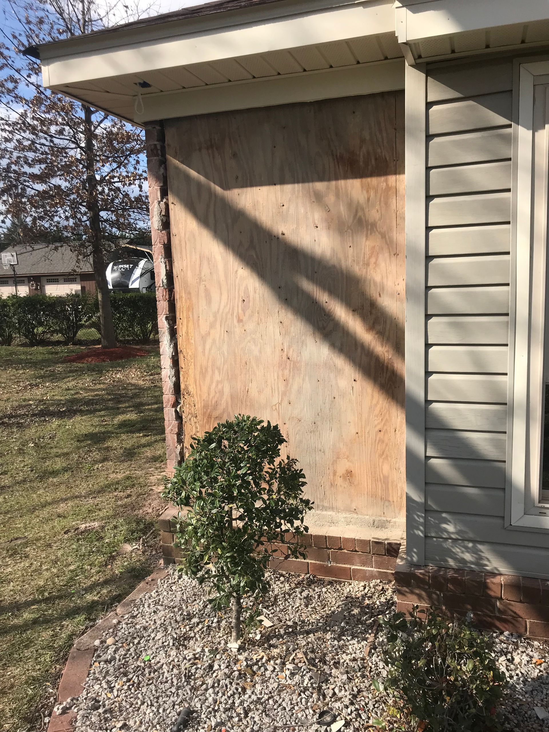 The side of a house with a tree in front of it.