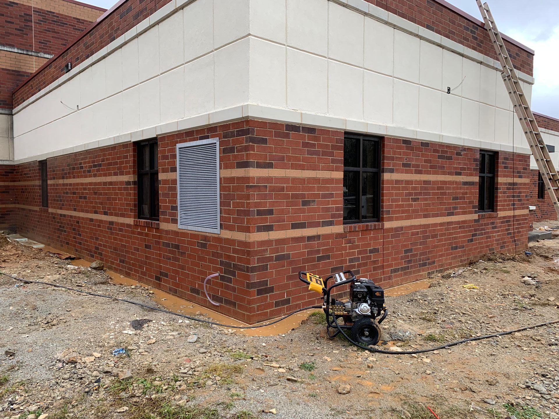A brick building with a pressure washer on the side of it.