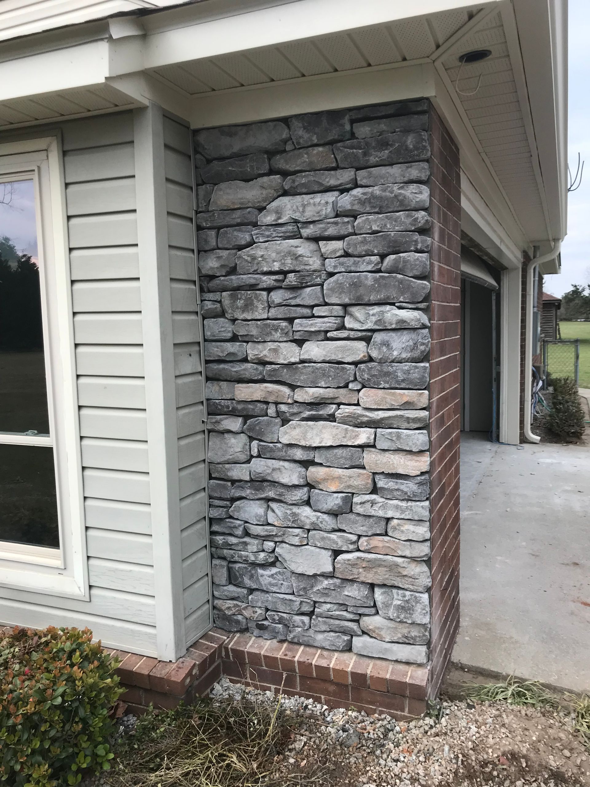 A house with a stone wall and a brick pillar
