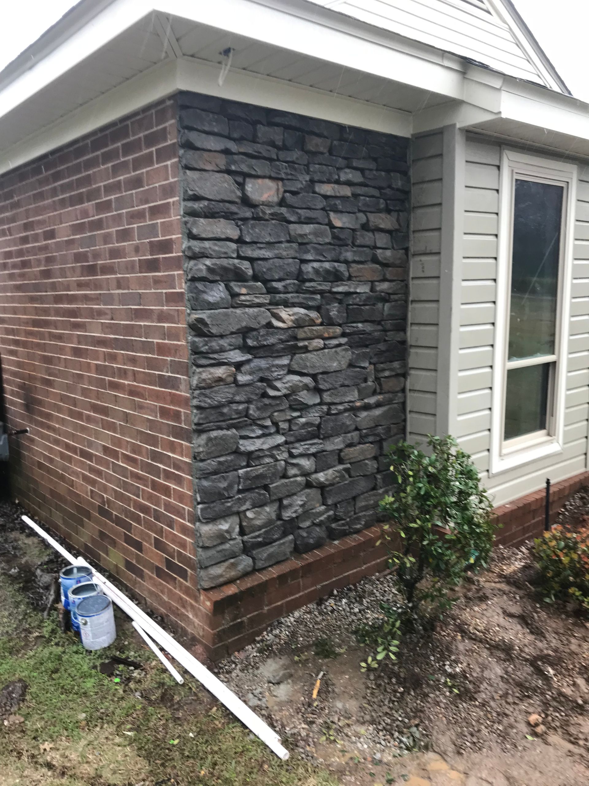A brick building with a stone wall and a window.