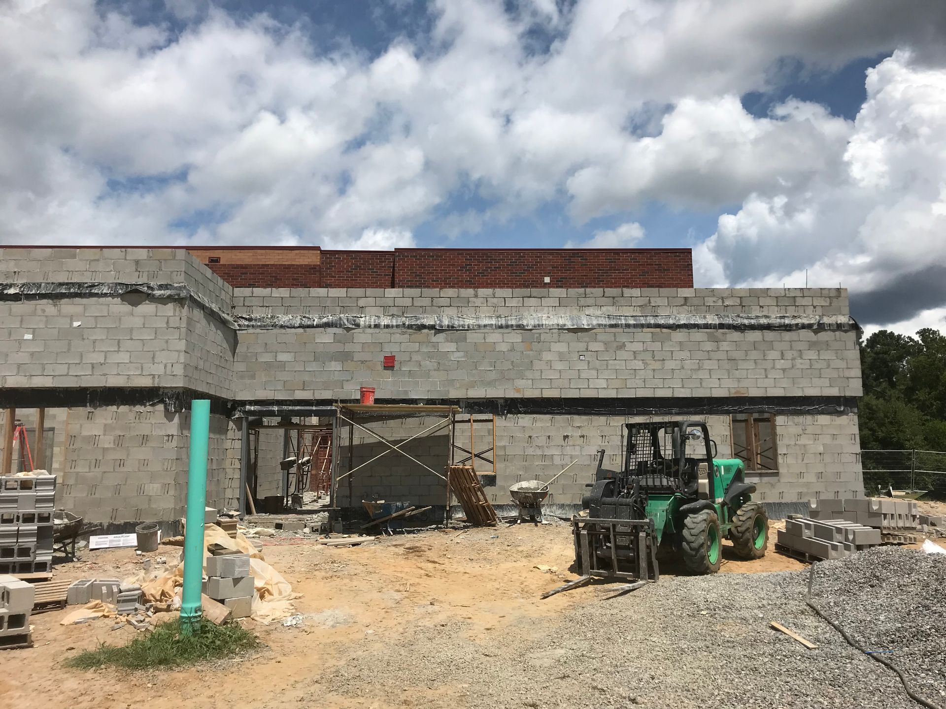 A tractor is parked in front of a building under construction.