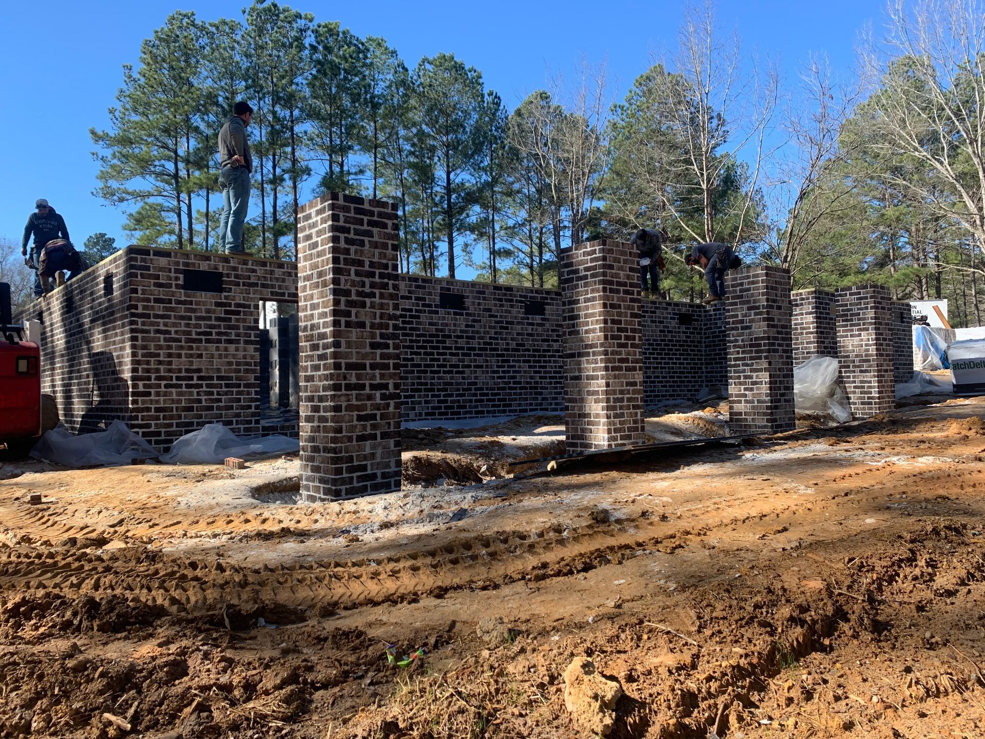 A brick building is being built in the middle of a dirt field.