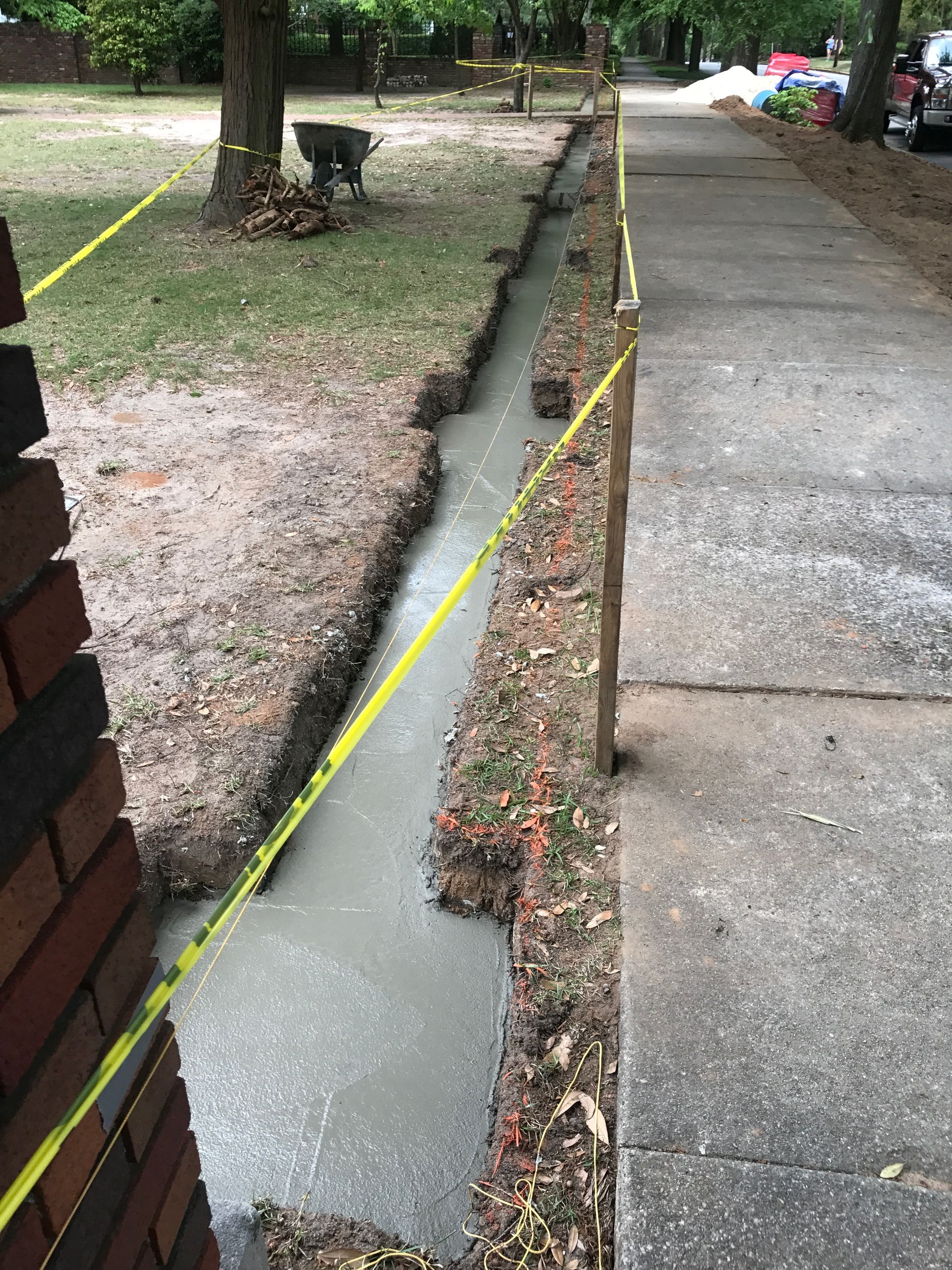 A sidewalk is being built next to a brick wall.