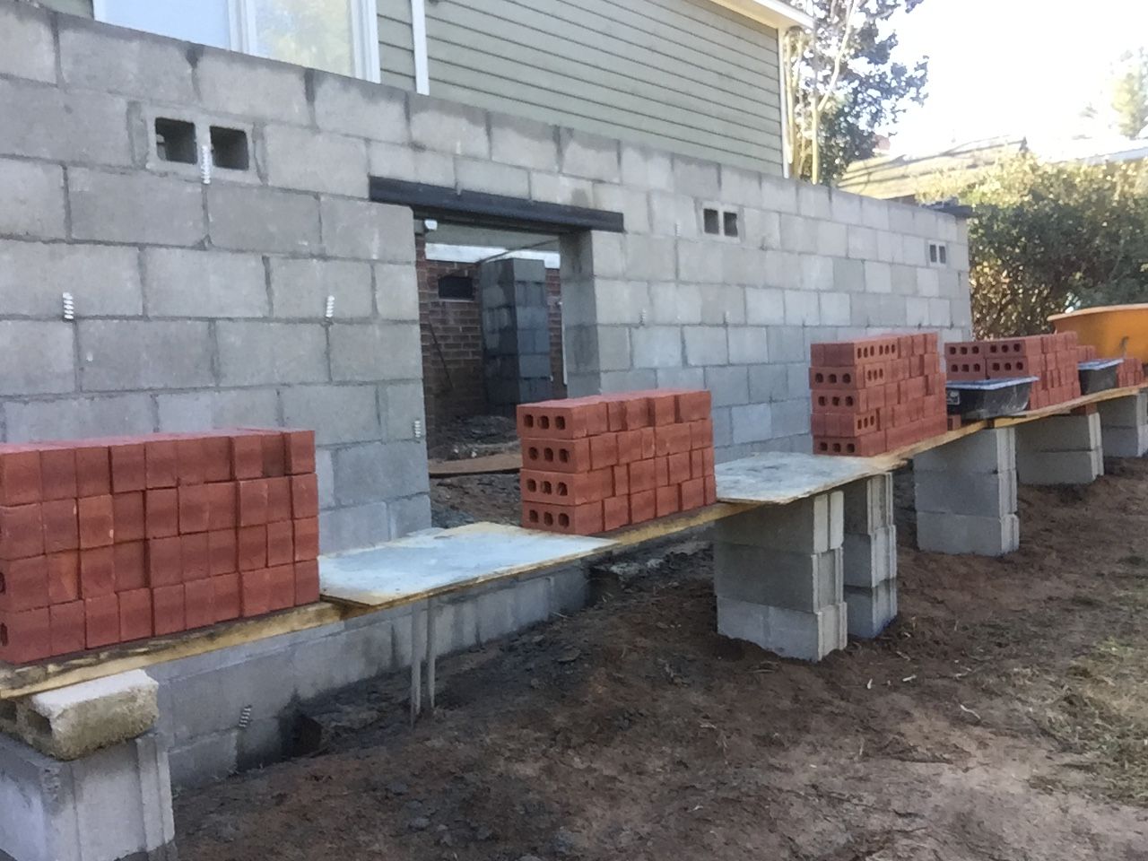 A row of bricks are sitting on a table in front of a building under construction.