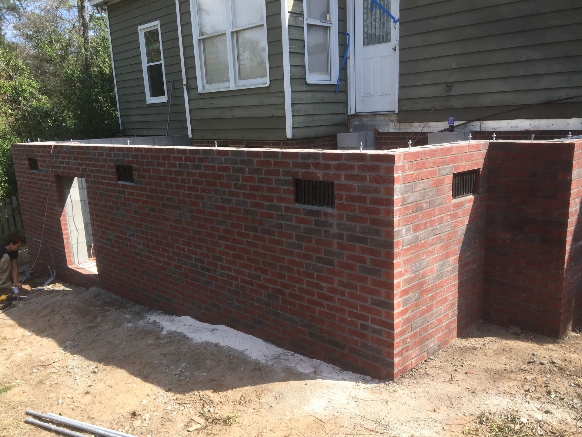 A brick wall is being built in front of a house.