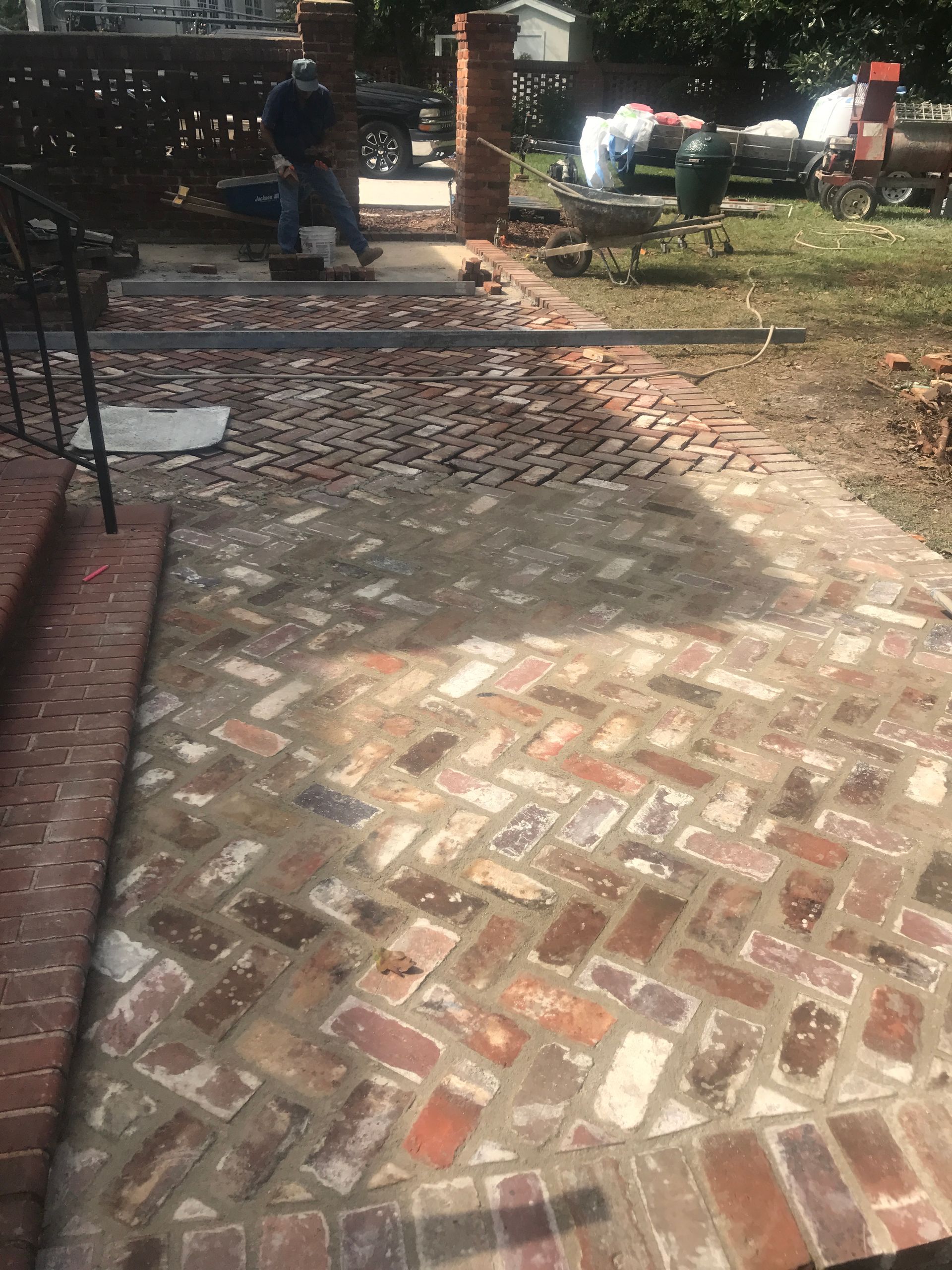 A brick walkway is being built in a backyard.