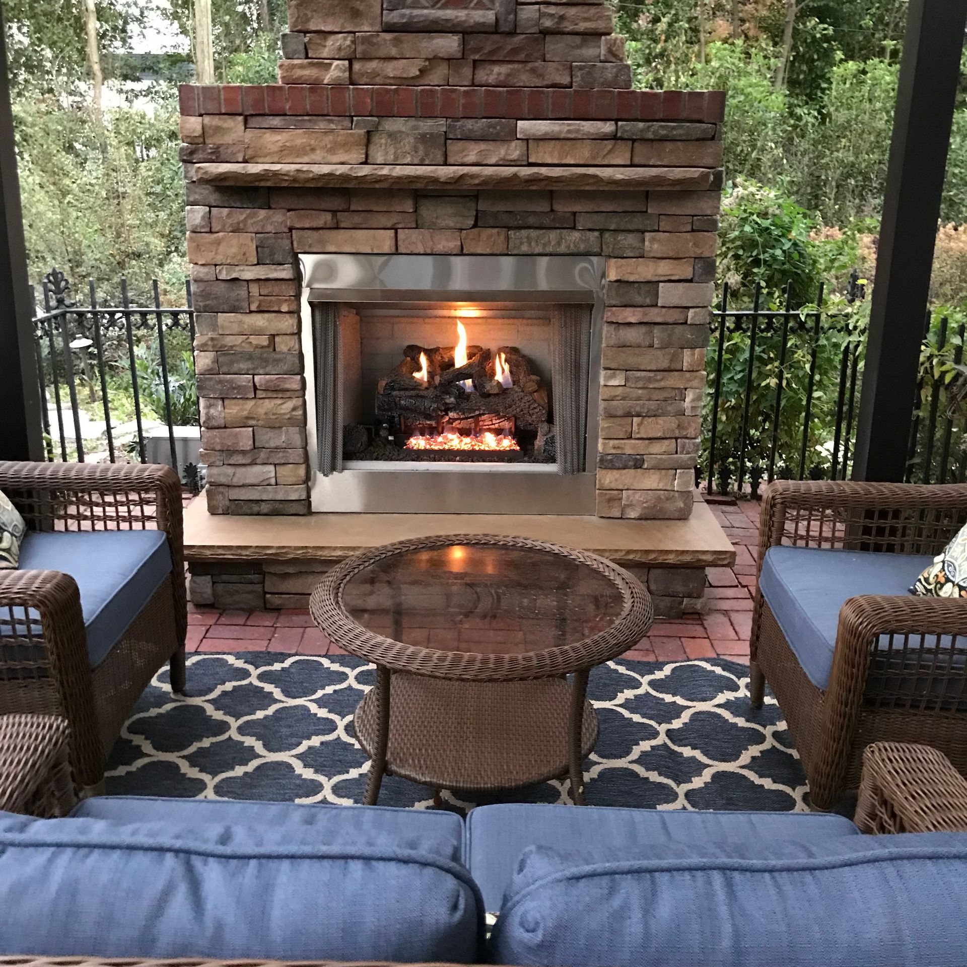 A patio with a fireplace and wicker furniture