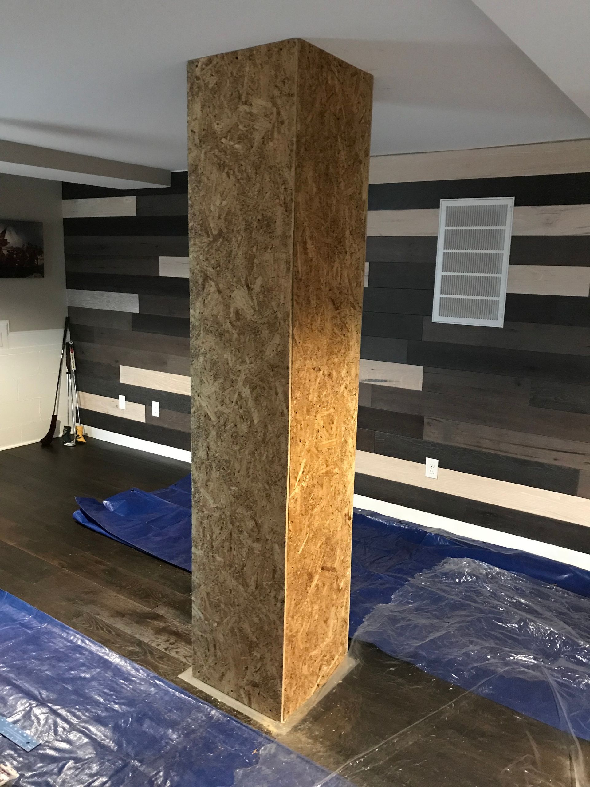 A pillar in a room with a blue tarp on the floor