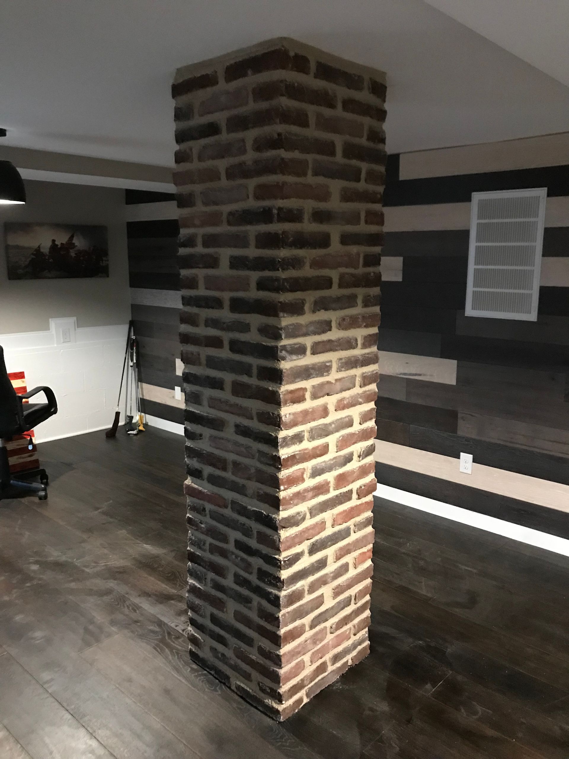 A large brick column is in the middle of a room.