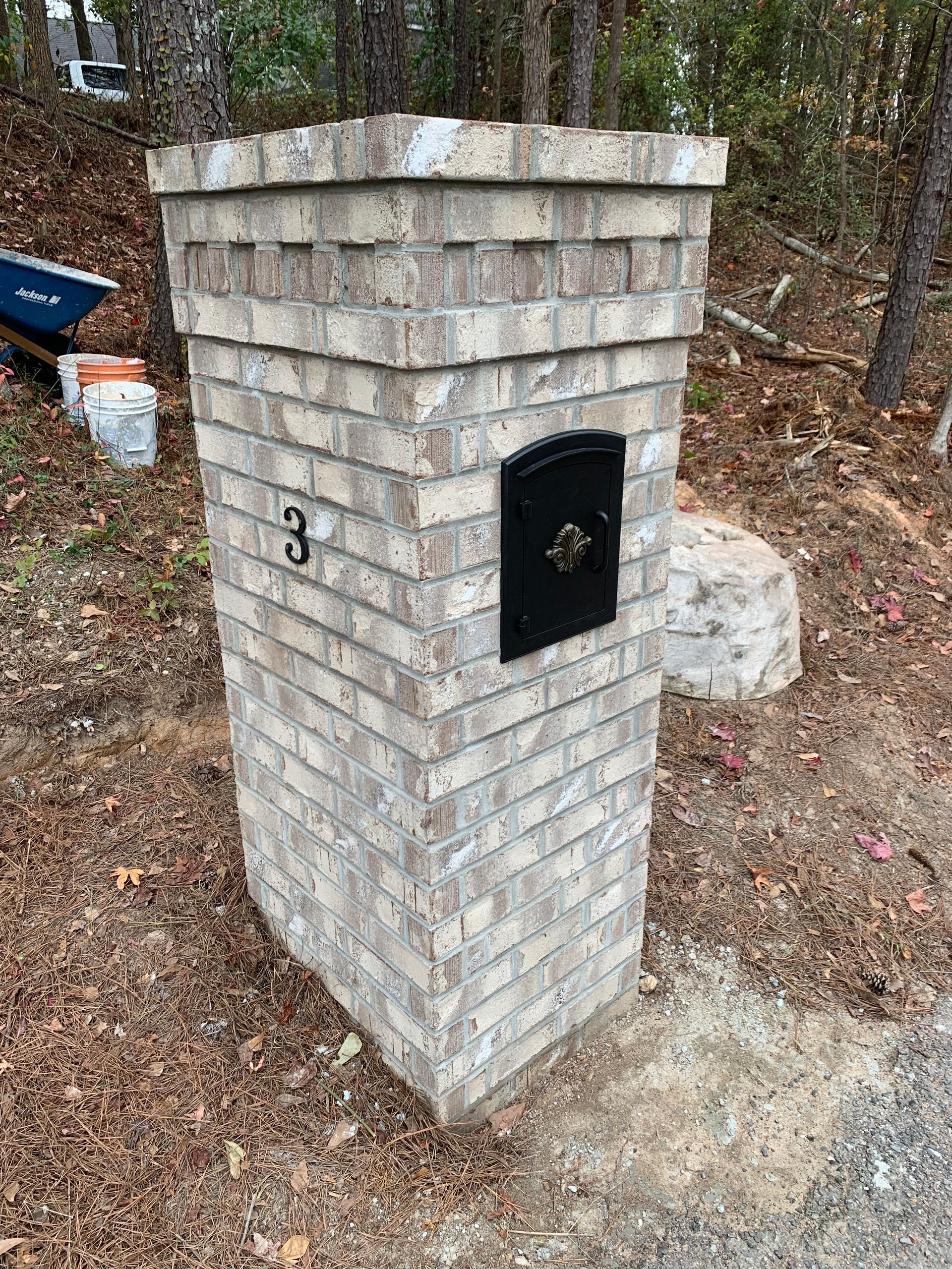 A brick mailbox is sitting on top of a brick pillar.