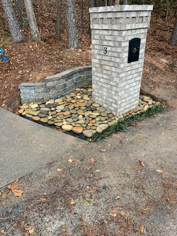 A brick post with a mailbox on top of it next to a driveway.