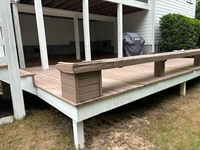 A wooden deck with a bench and a grill in the backyard of a house.