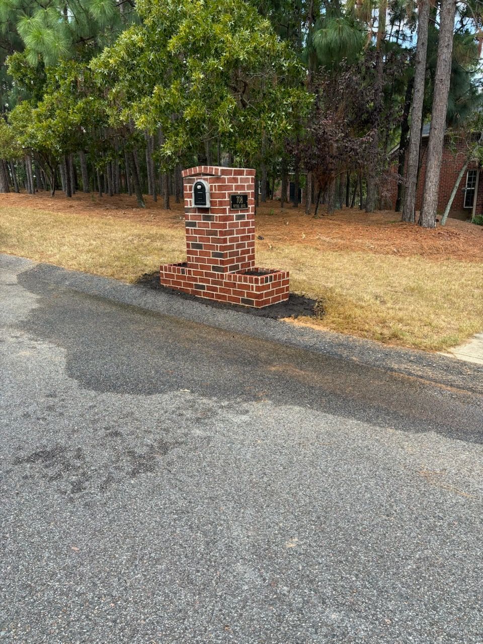 A brick chimney is sitting on the side of a road.