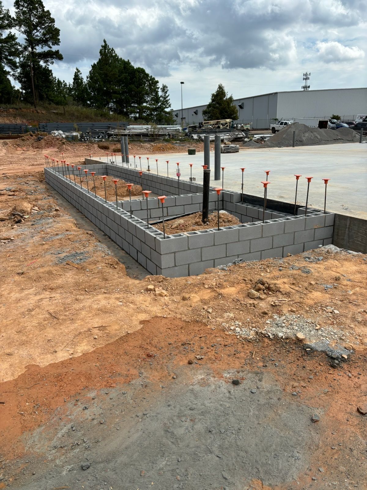 A brick wall is being built in a dirt field.
