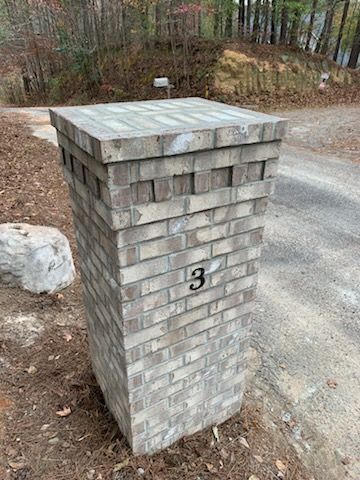 A brick column with the number 3 on it is sitting on the side of a road.