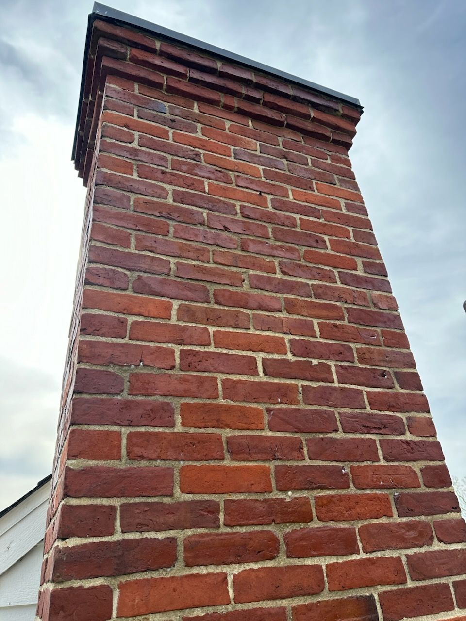 A tall red brick chimney on top of a house.