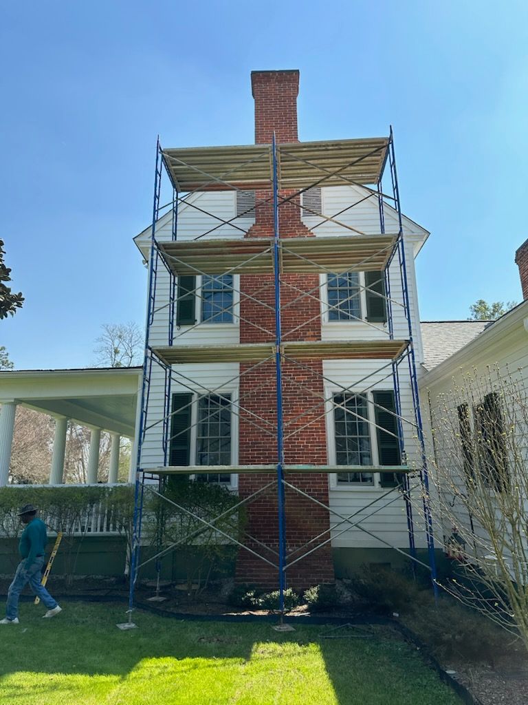 A man is standing in front of a house with scaffolding around it.