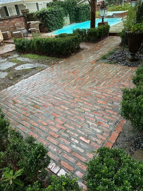A brick walkway leading to a pool in a backyard.