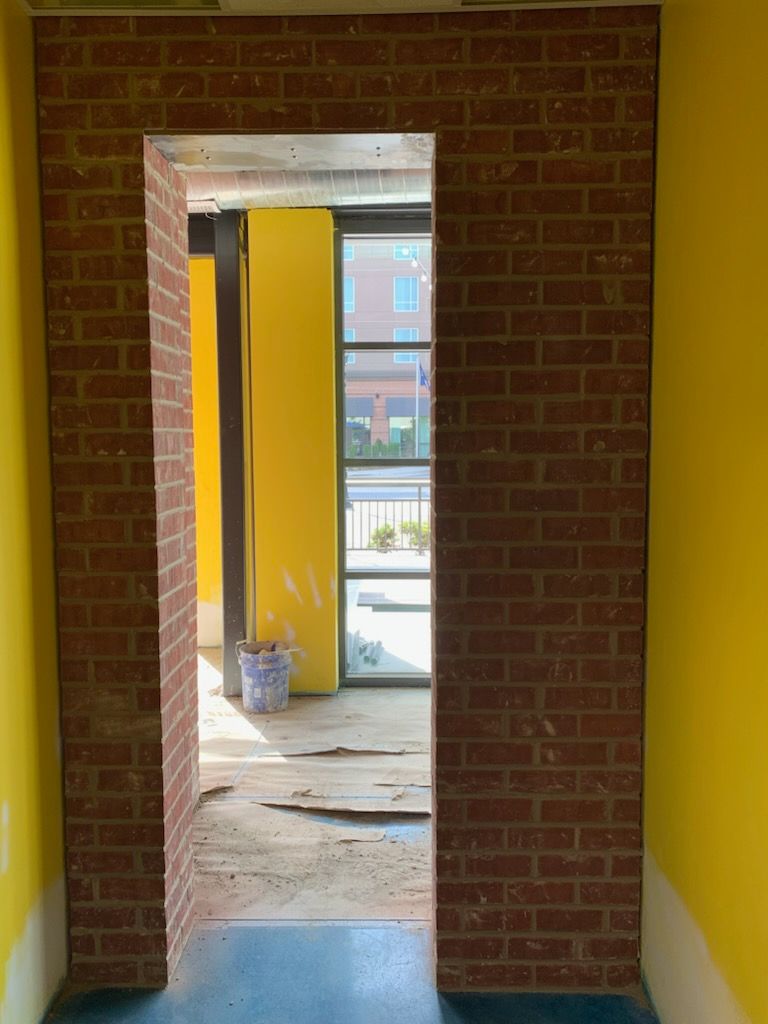 There is a brick wall in the middle of a room with yellow walls.