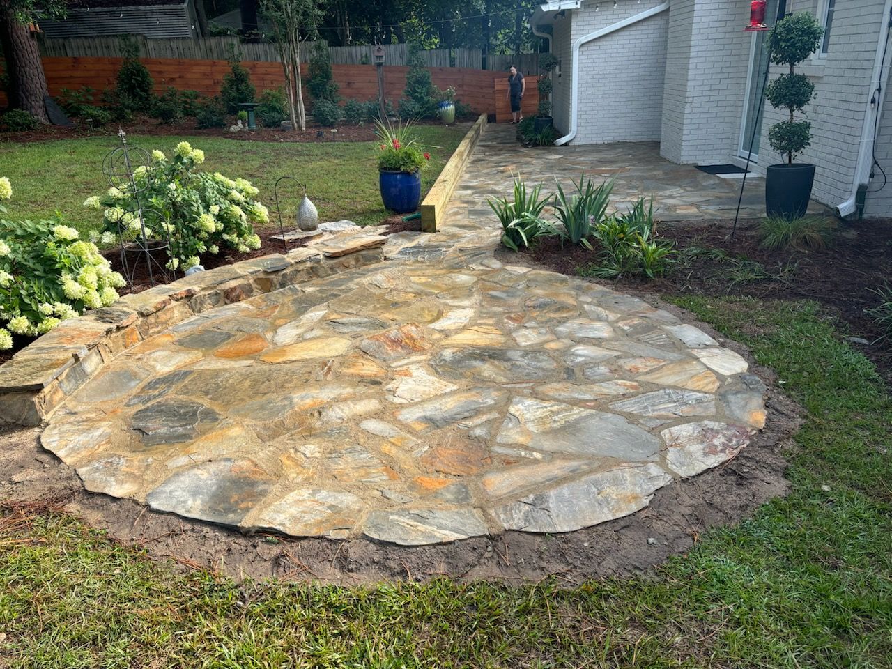 A stone patio is sitting in the middle of a lush green yard.