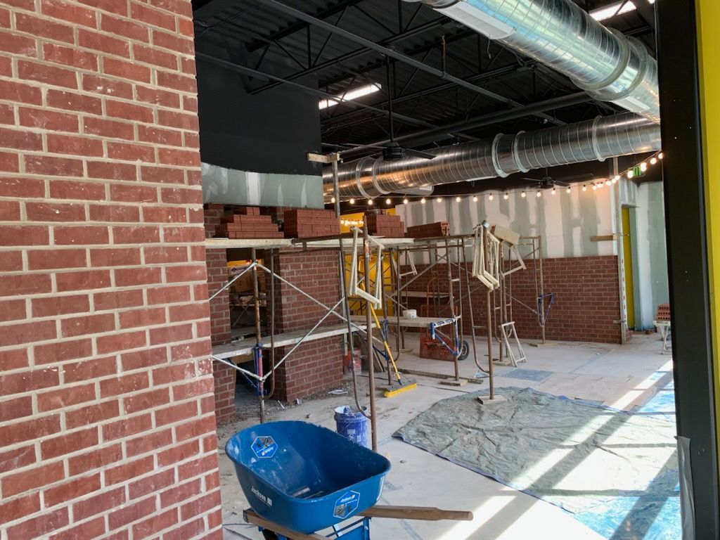 A blue wheelbarrow is sitting next to a brick wall in a building under construction.