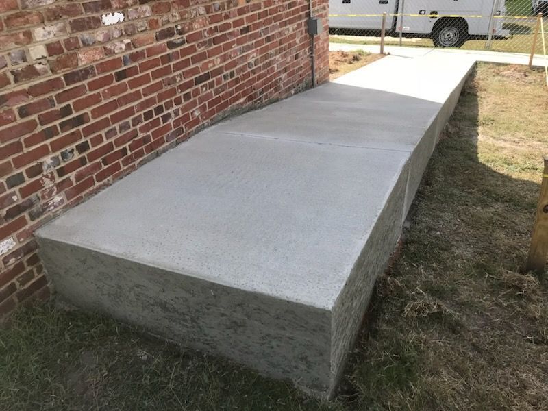 A concrete block is sitting next to a brick wall.