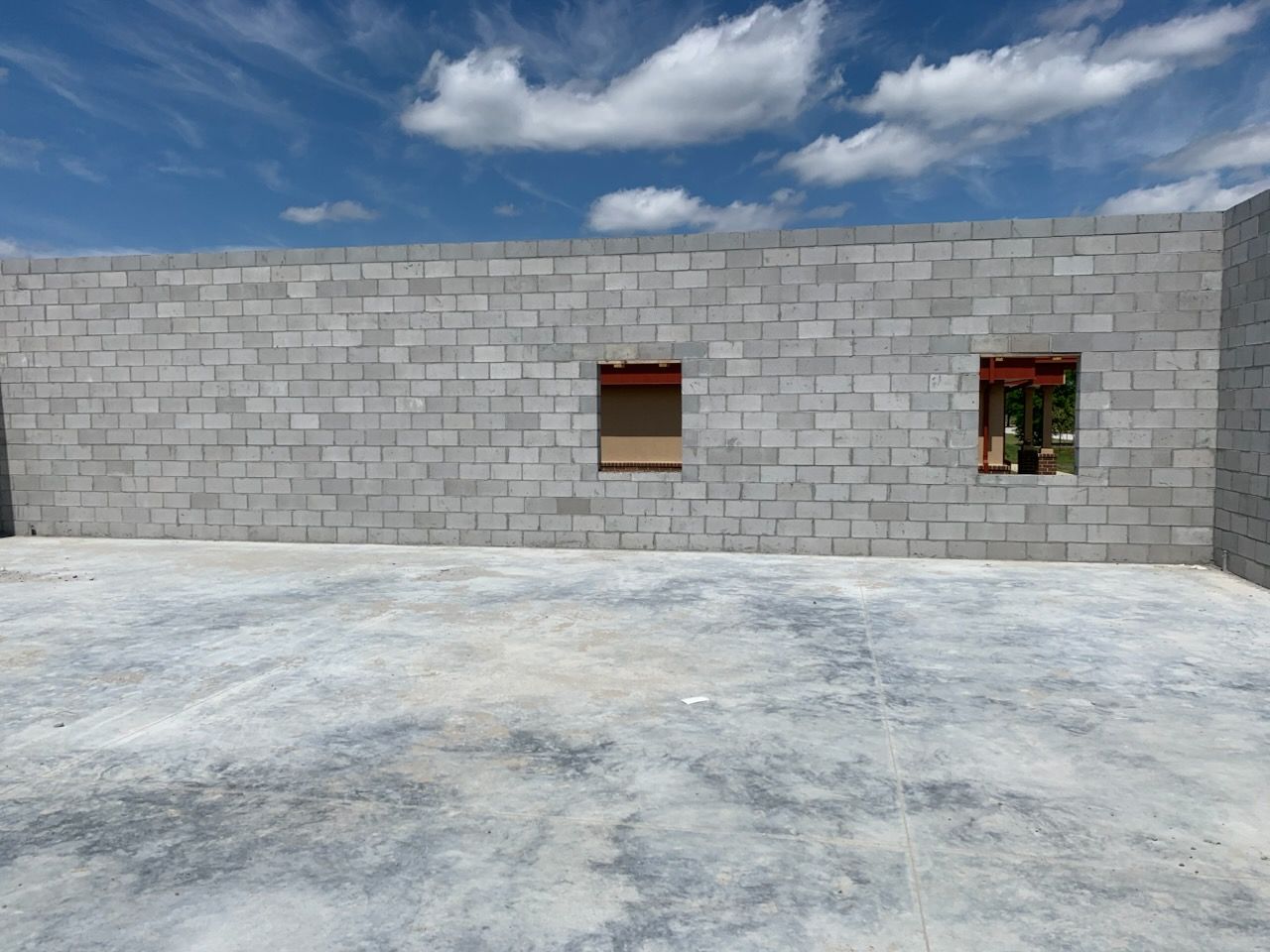 A brick wall with a concrete floor and a blue sky in the background.