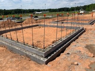 A concrete foundation is being built in a dirt field.