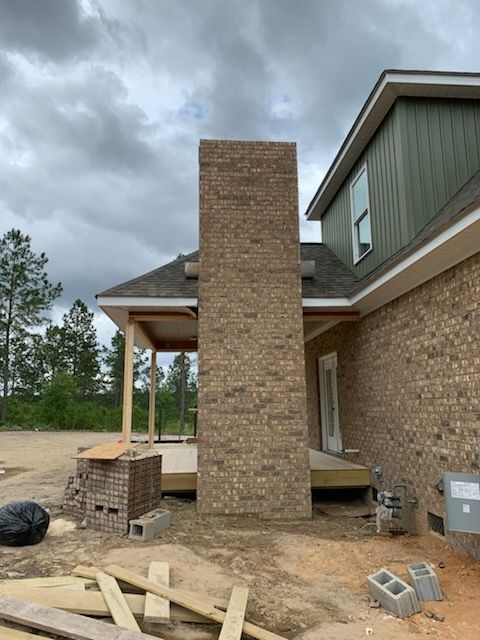 A brick chimney is being built on the side of a house.