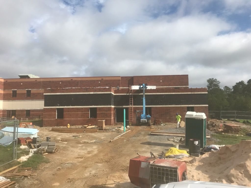A large brick building is being built in a dirt field.