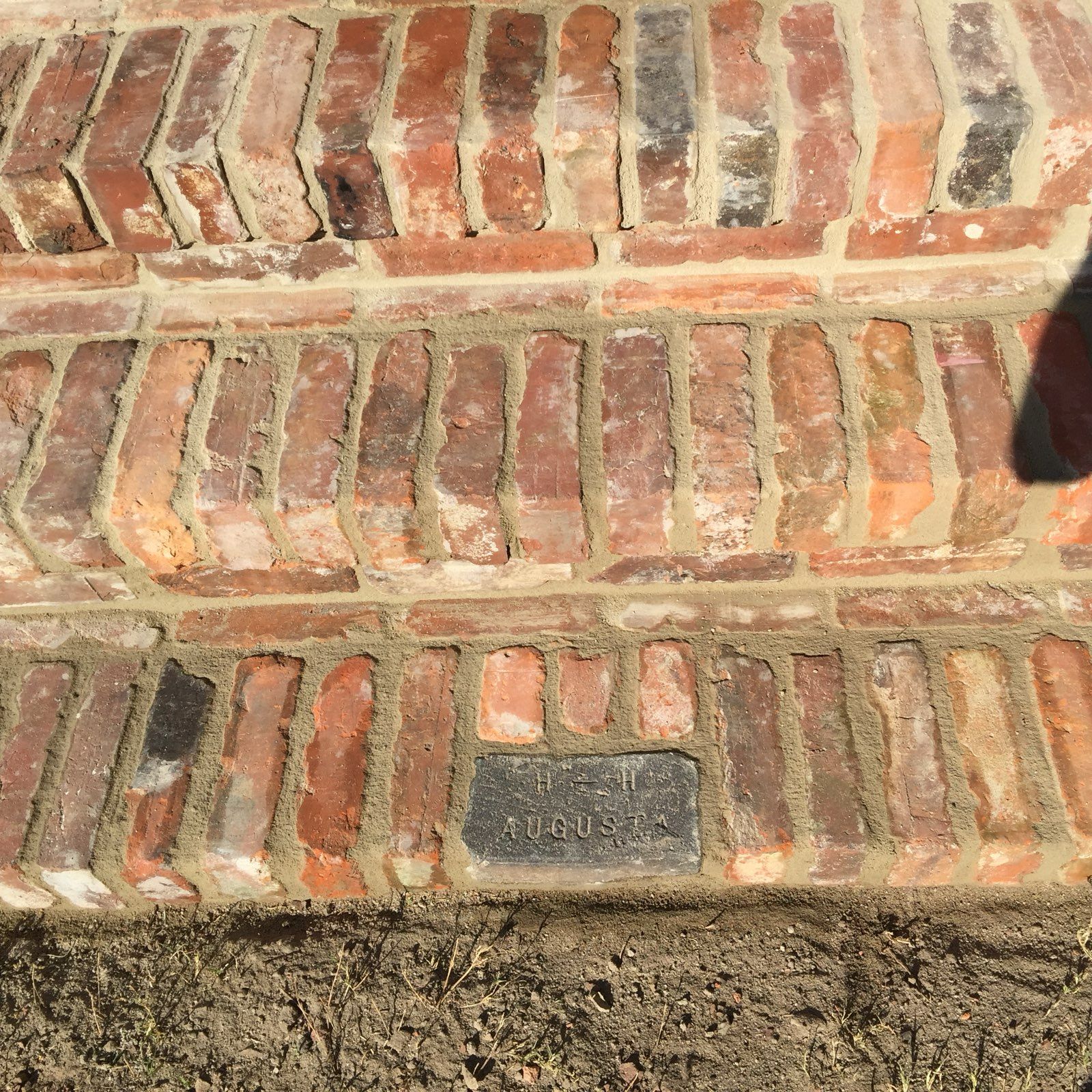 A close up of a brick walkway on a dirt road.
