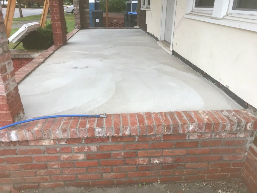 A concrete porch is being built next to a brick wall.