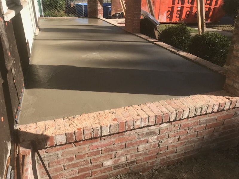 A brick wall is surrounding a concrete walkway.