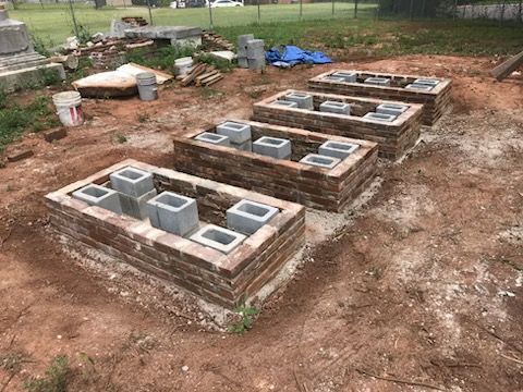 A row of bricks and concrete blocks sitting on top of a dirt field.