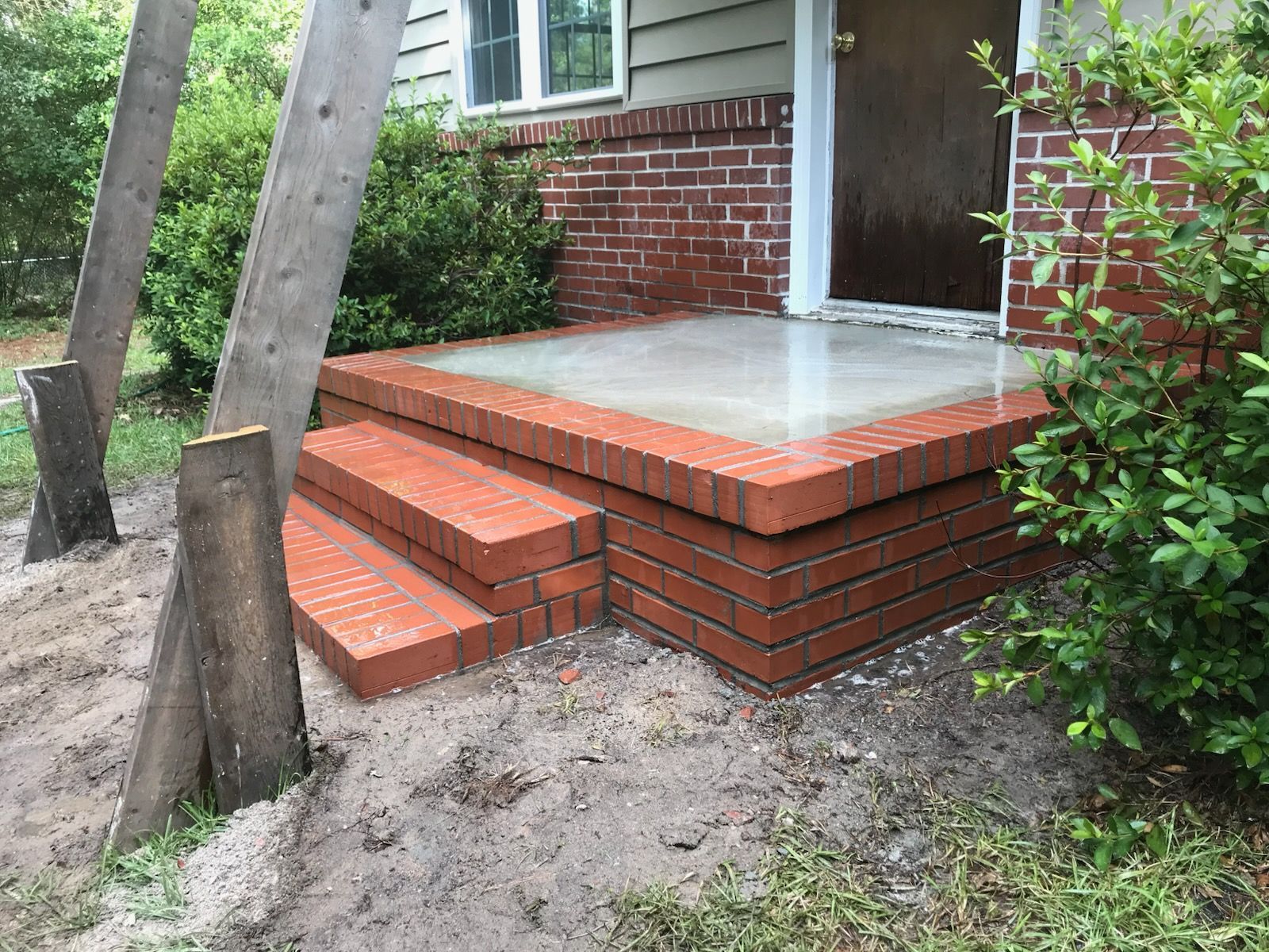 A brick porch with steps leading to the front door of a house.