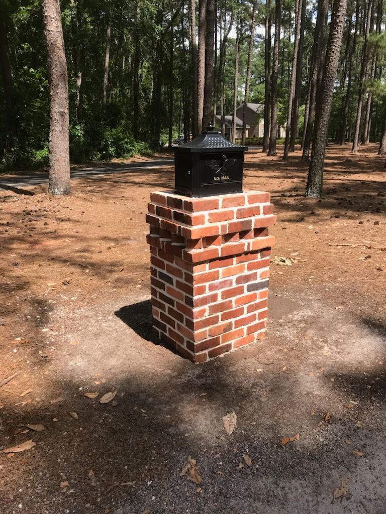 A brick chimney is sitting in the middle of a forest.