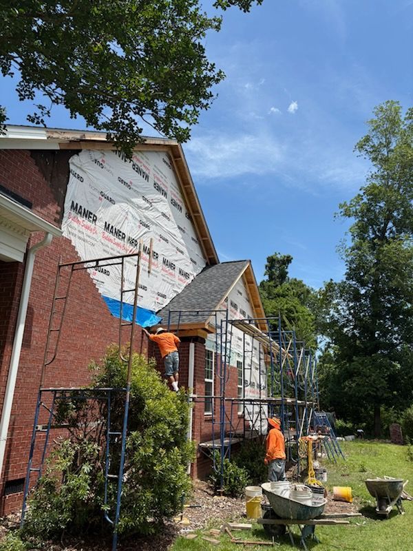 A brick house is being remodeled with scaffolding and a roof.