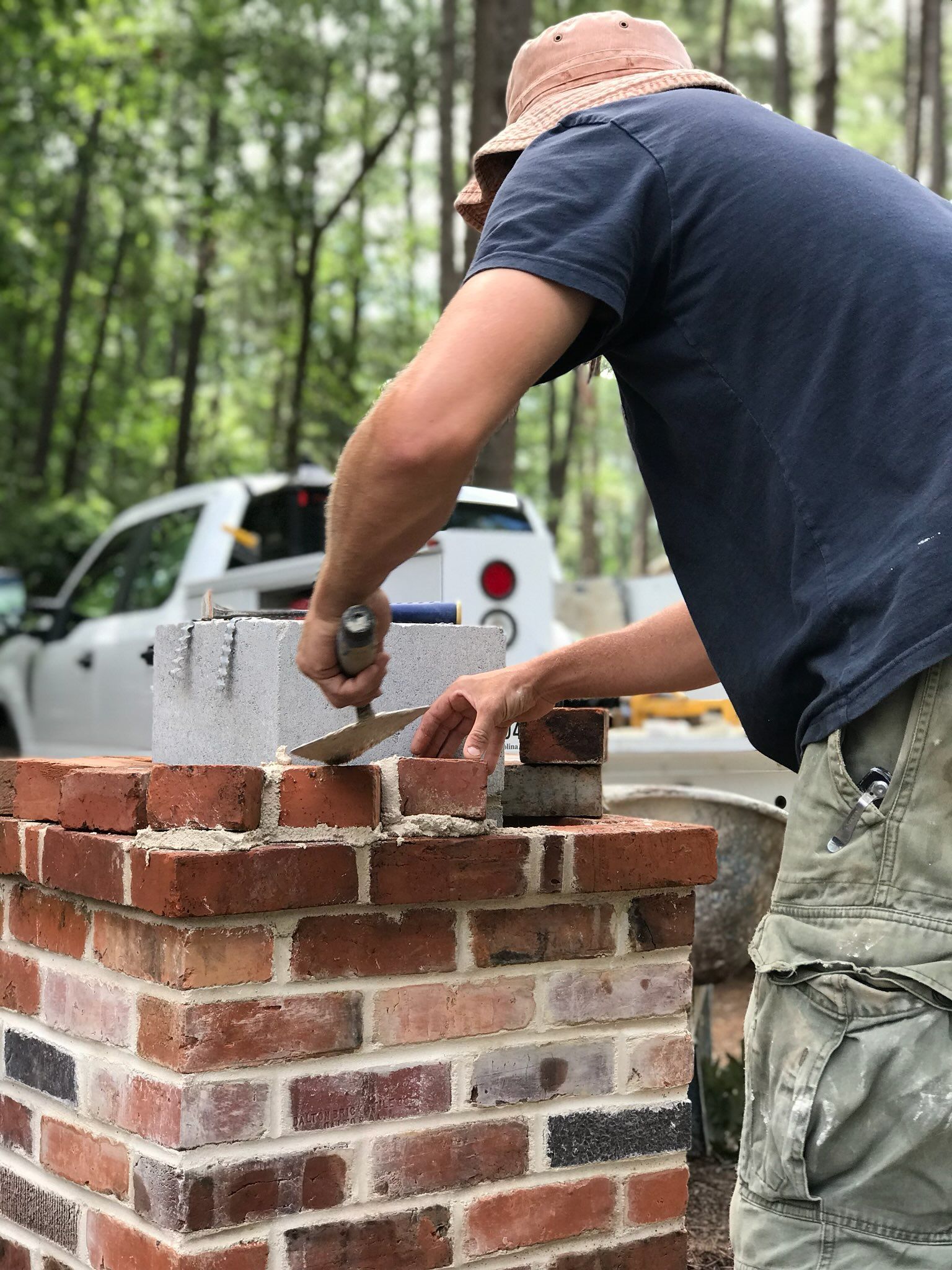 A man is laying bricks on top of a brick wall.