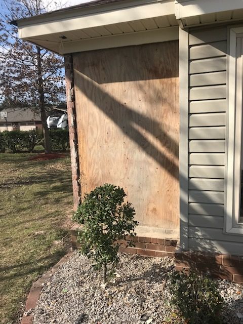 The side of a house with a tree in front of it.
