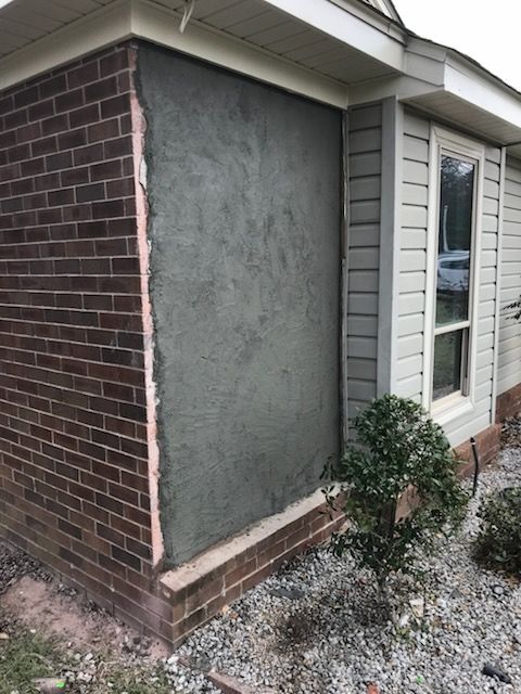 A house with a brick wall and a white siding is being remodeled.