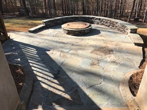 A stone patio with a fire pit in the middle of it.