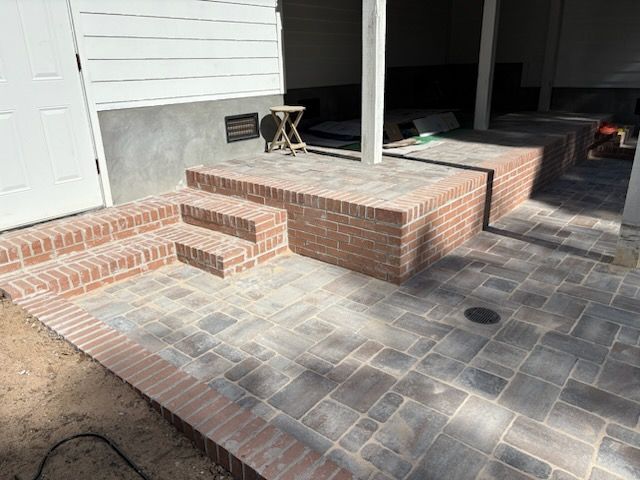 A patio with brick steps leading up to a porch.