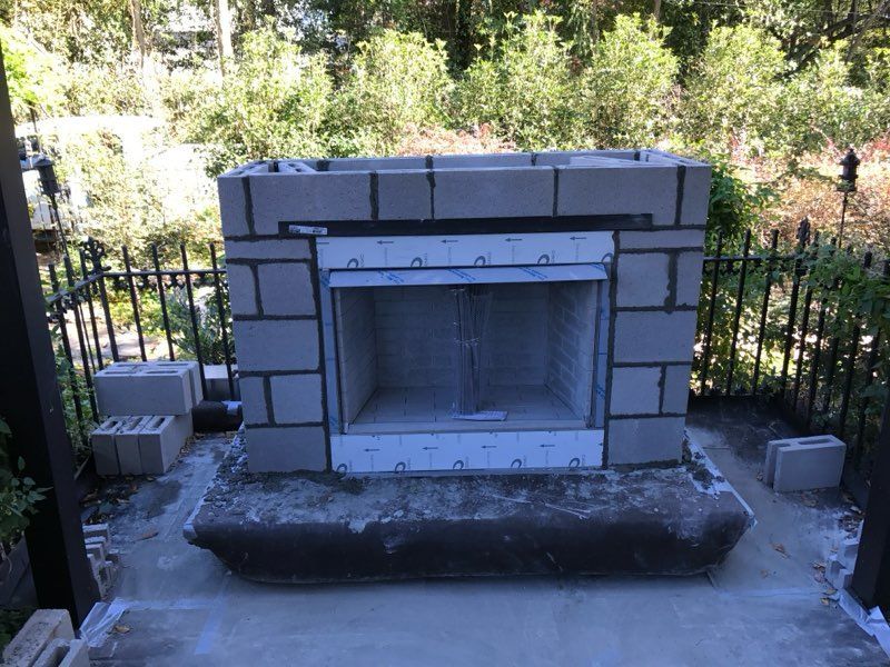 A brick fireplace is being built in a backyard
