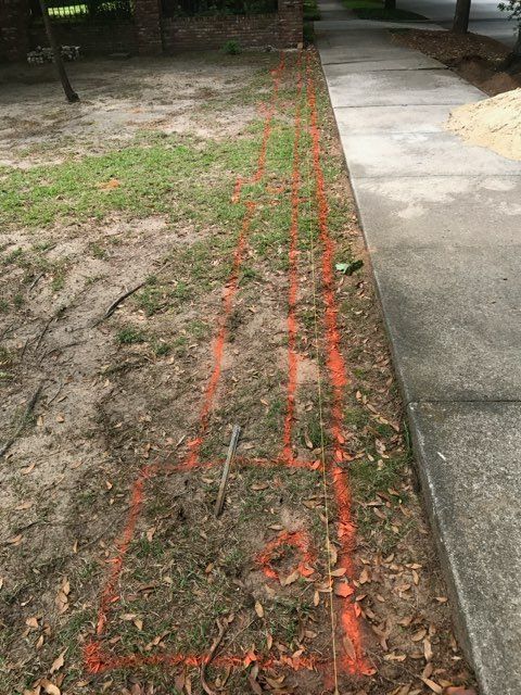 A concrete sidewalk next to a grassy field with a red line drawn in the grass.