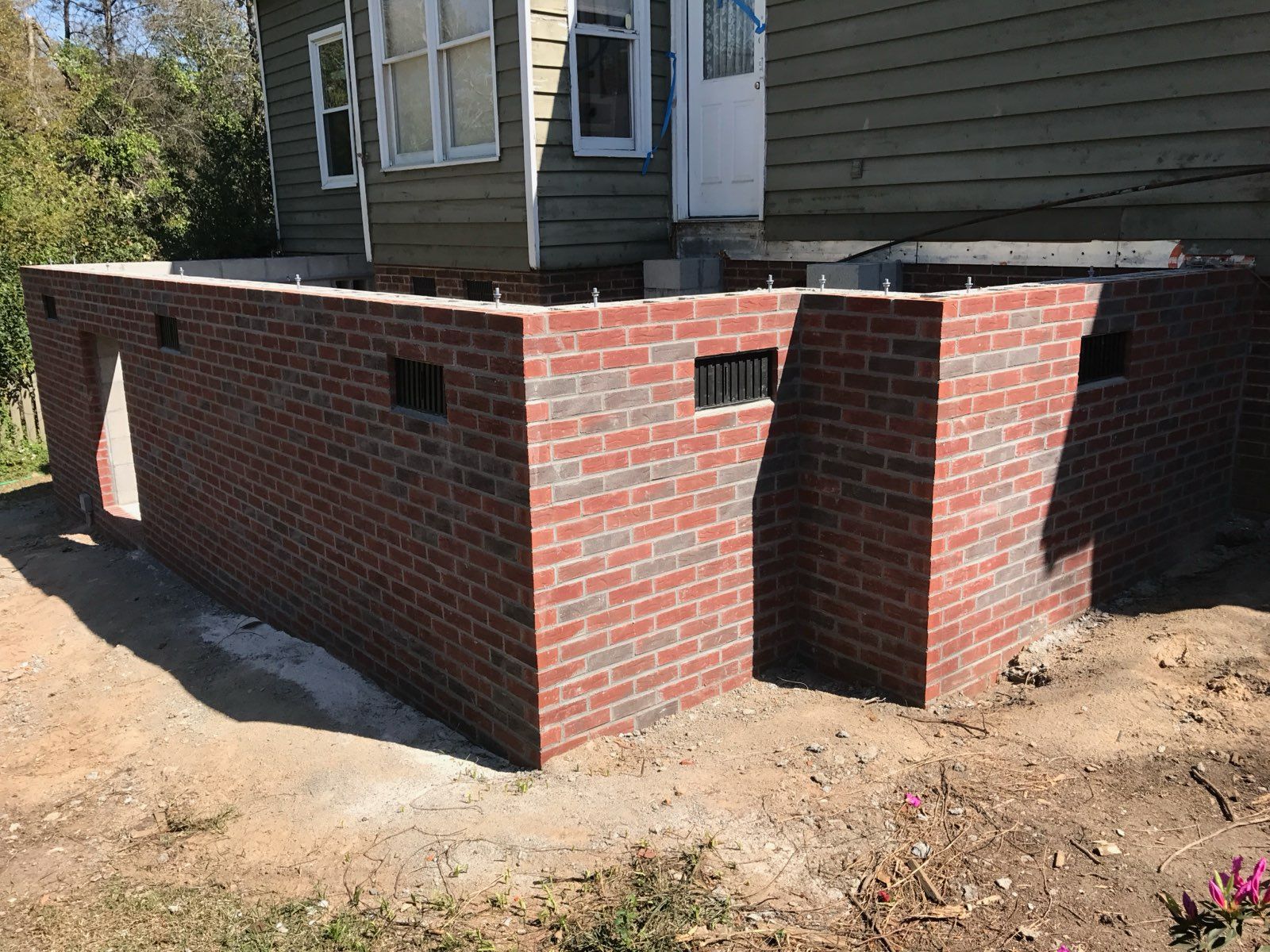 A brick wall is being built in front of a house.