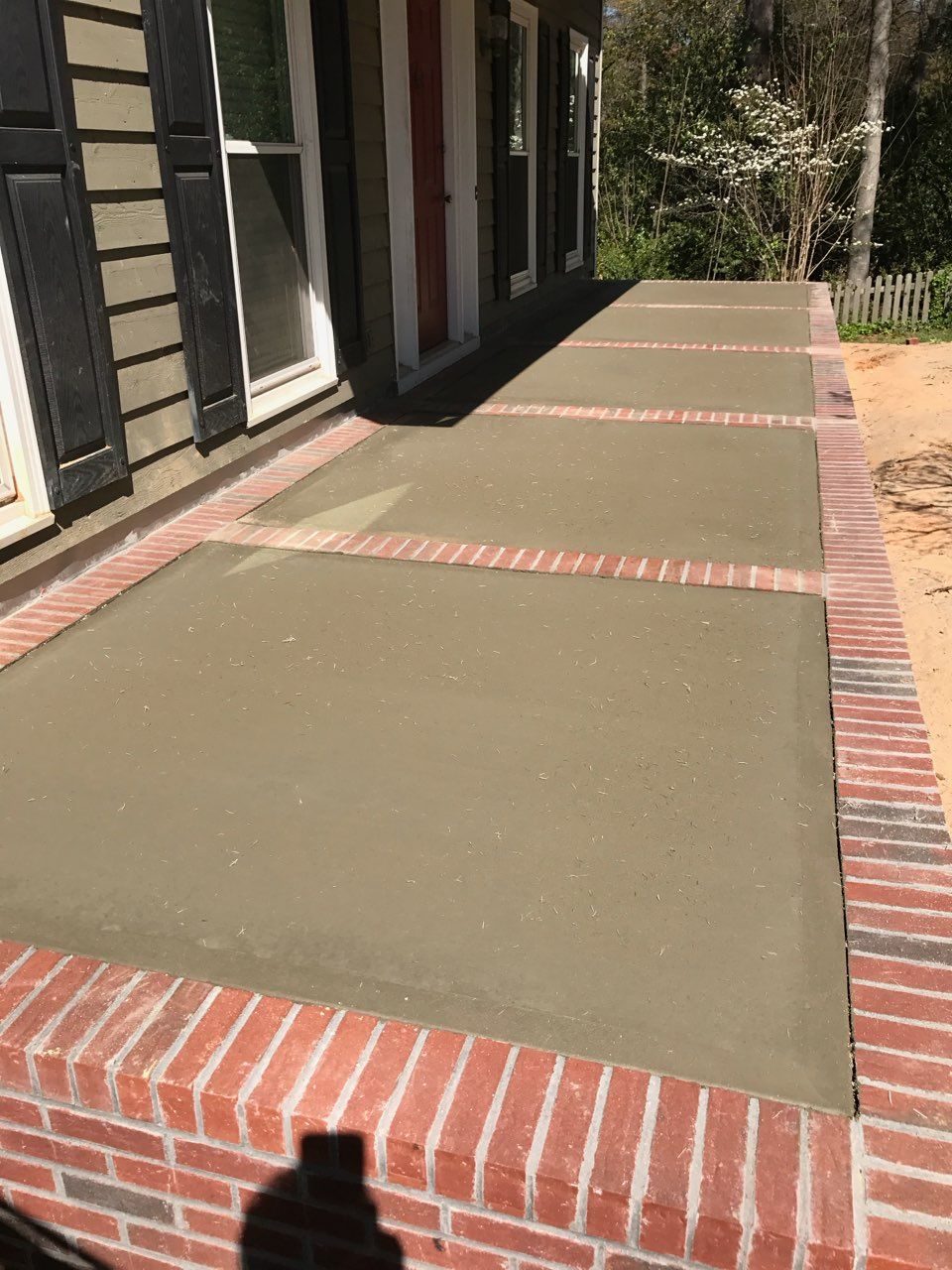 A brick walkway with a concrete walkway in front of a house.